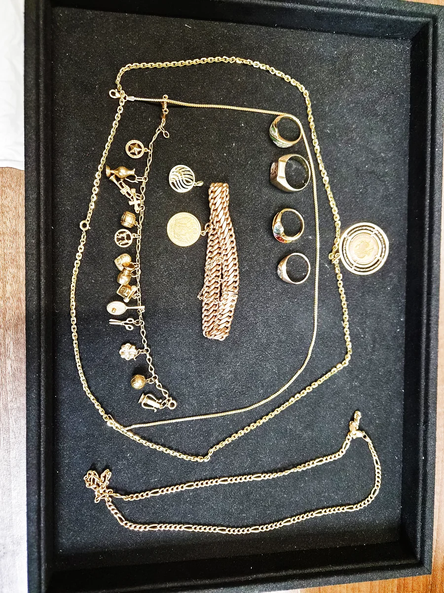 Goldschmuck-Nachlass mit Halsketten, Siegelringen, Bettelarmband und Münzanhänger auf dem Vorlageteller