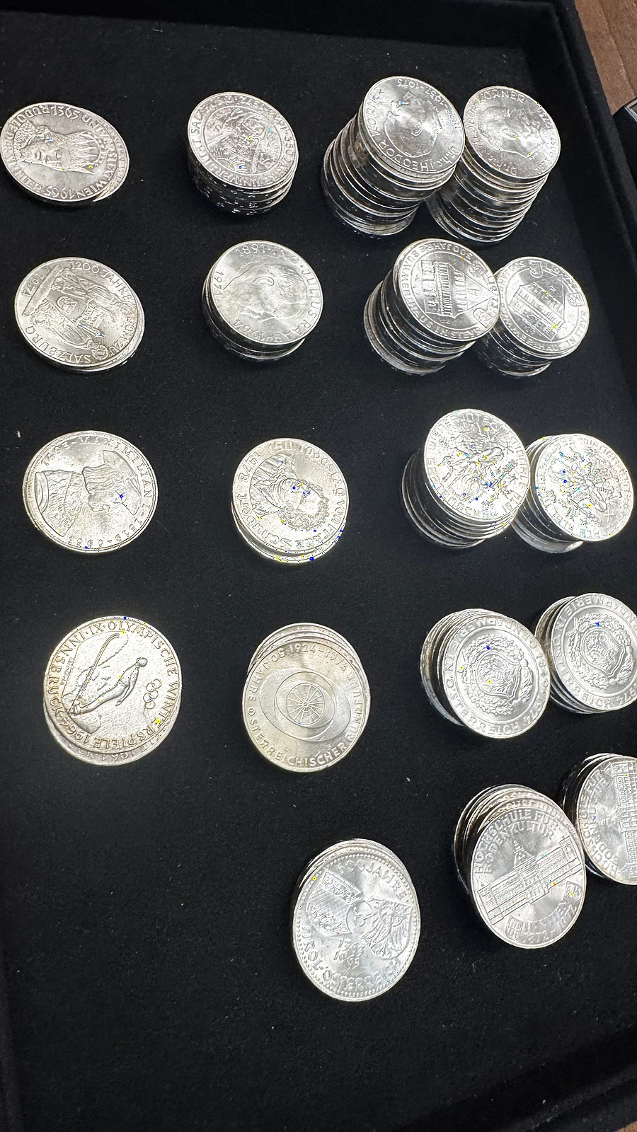 Stapel österreichischer 50- und 100-Schilling-Silbermünzen auf schwarzem Samt bei Gold & More